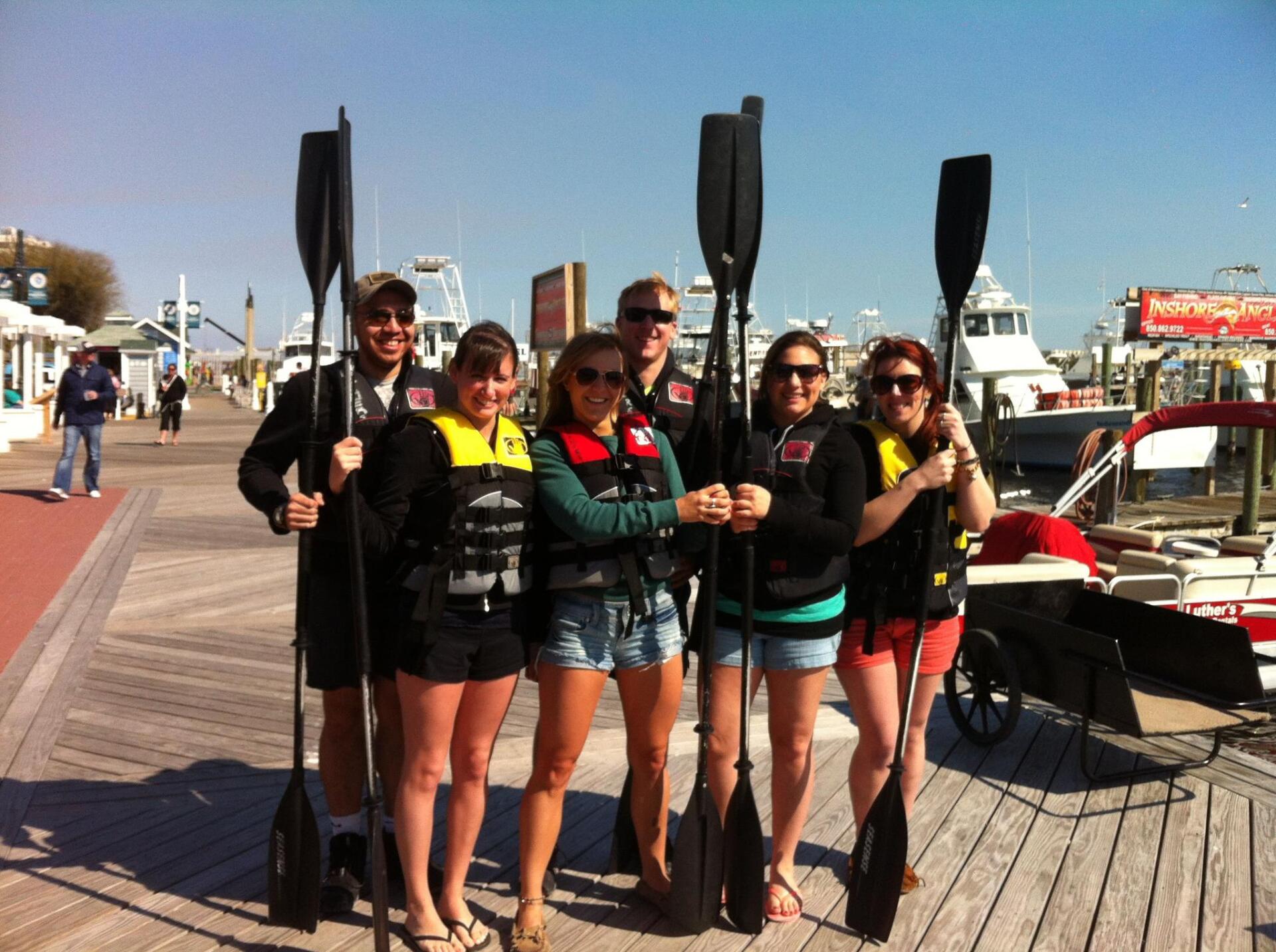 Friends holding kayak paddles on the harbor boardwalk