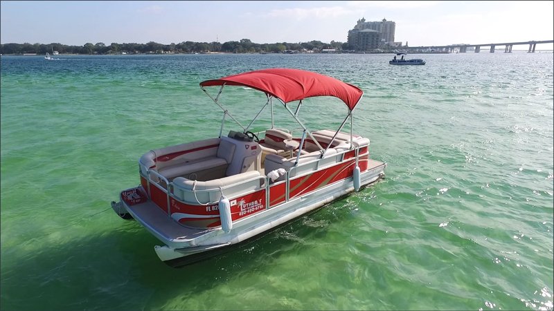 A red and white Luther's pontoon anchored in emerald water