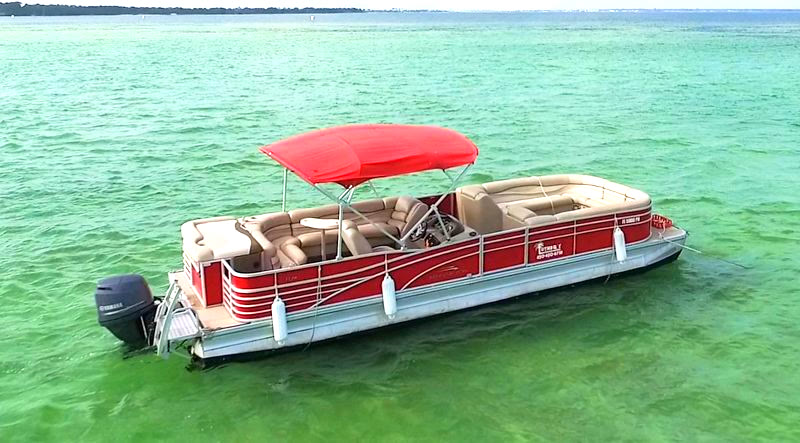 A Luther's pontoon with a red bimini top on clear green water